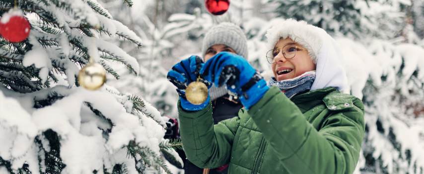 Travellers enjoying white Christmas decorating a tree