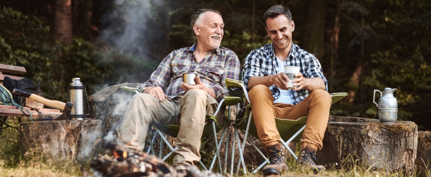 Two men sitting by a campfire in the woods