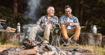 Two men sitting by a campfire in the woods