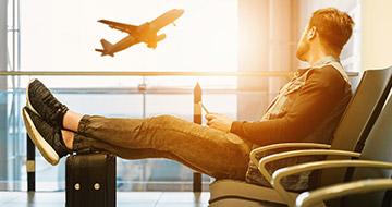 man waiting at airport with carry-on luggage