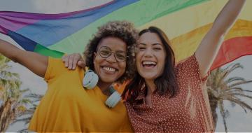 Two ladies with the LGBTQ+ flag